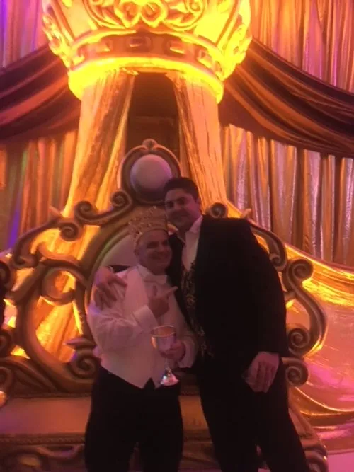 Two guests posing beside a Mardi Gras throne