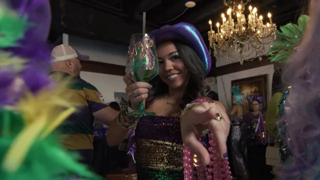 A guest raising a decorated cup during a Mardi Gras celebration